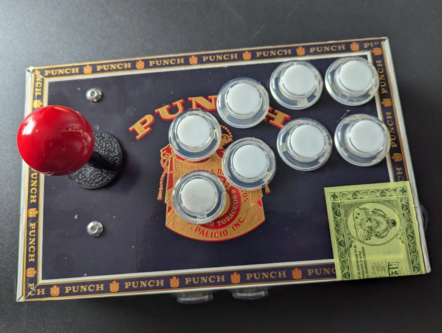 A Raspberry pi pico wired up to a joystick and some buttons on the inside of a cigar box.