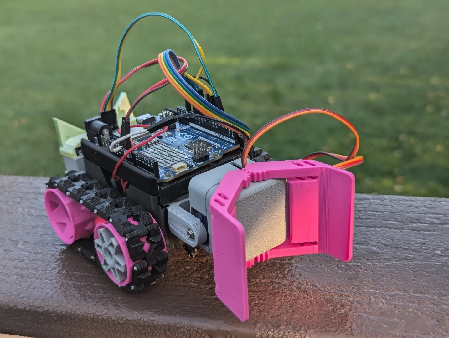 A small 3D printed rover style robot. It has sensors on the front housed in an enclosure that looks like a cat's head.